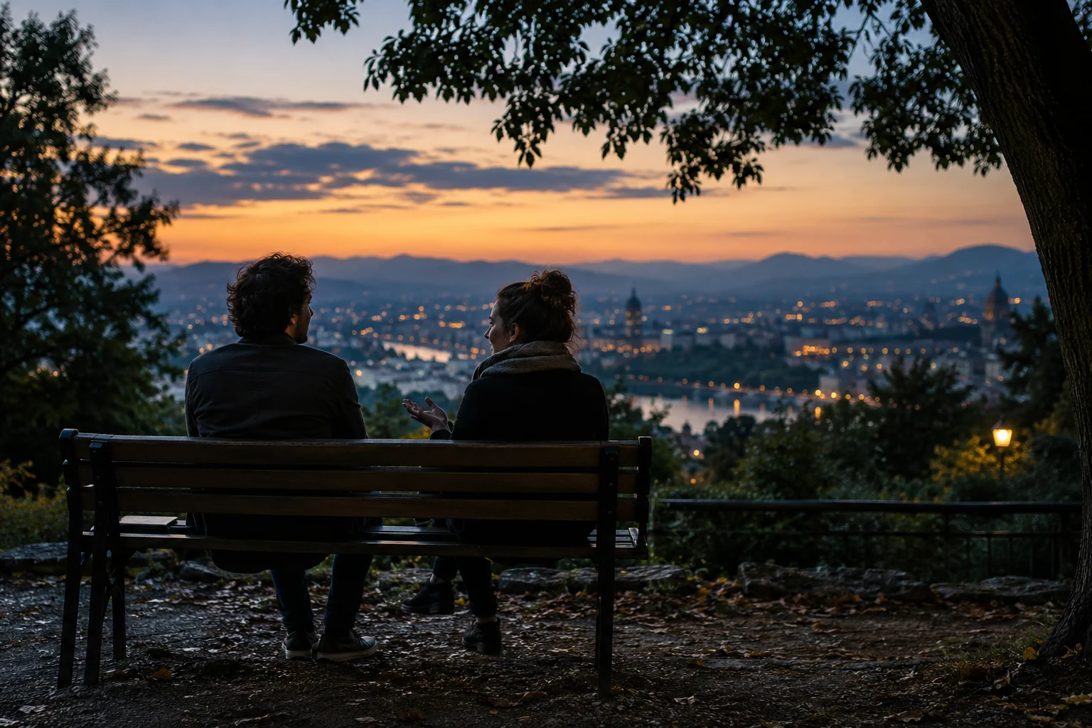 Two friends on a park bench overlooking a city at dusk